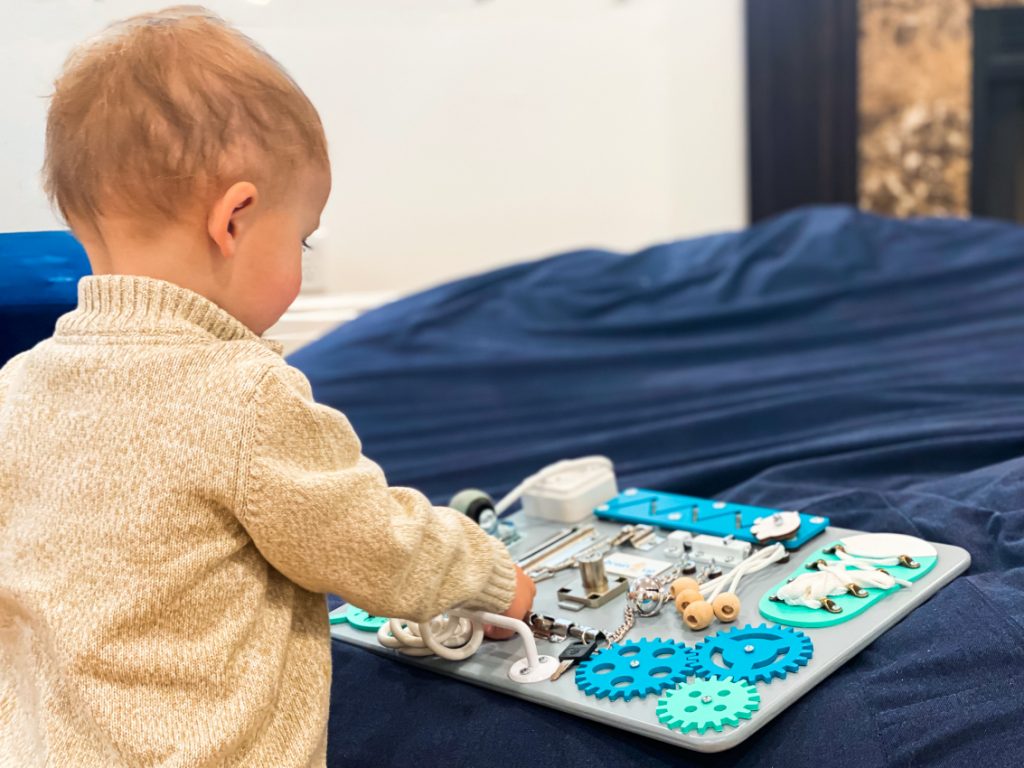 Toddler playing with a busy board.