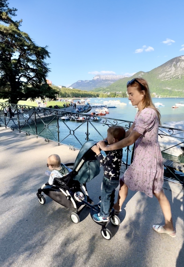 Mom pushing a stroller with a toddler using a buggy board