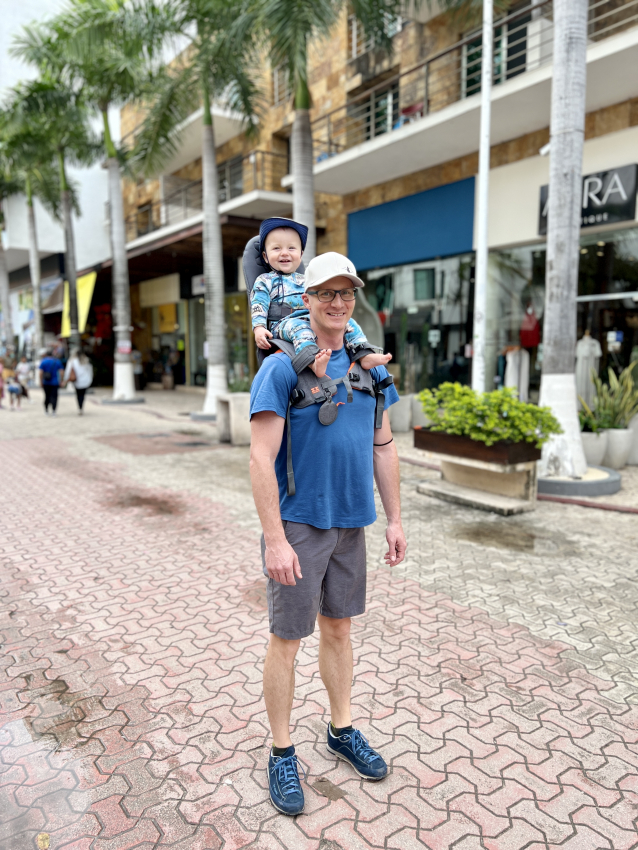 Child in over the shoulder baby carrier.