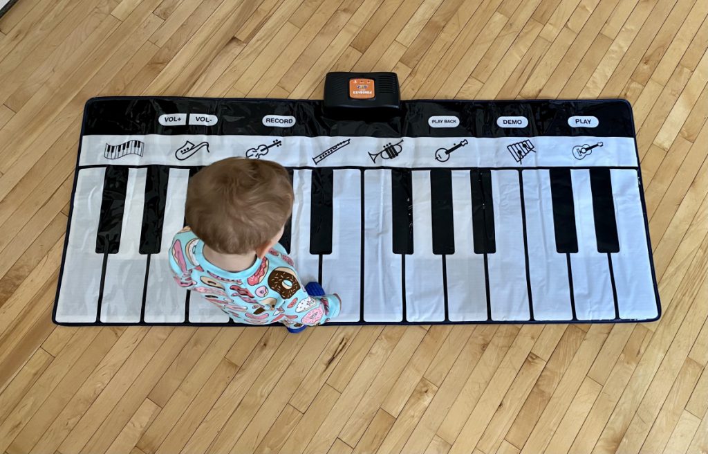 Child playing on a rollable portable piano matt.