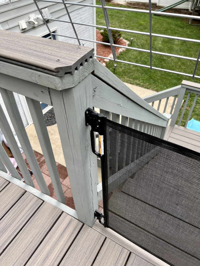 Retractable baby gate at the top of wooden staircase.