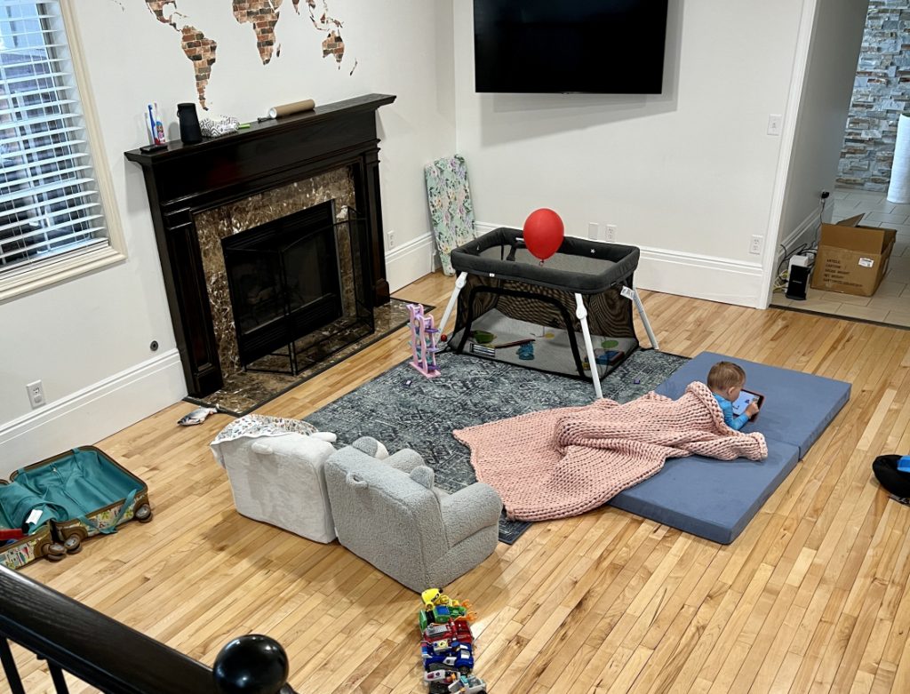 Baby gates installed for fireplace where toddler is watching ipad video in a living room.