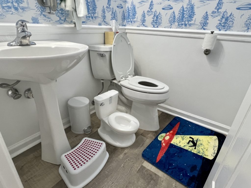 White step stool for toddlers in front of a wash basin.