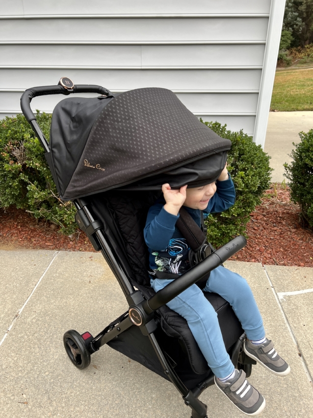 Toddler sitting in a travel stroller playing with a canopy