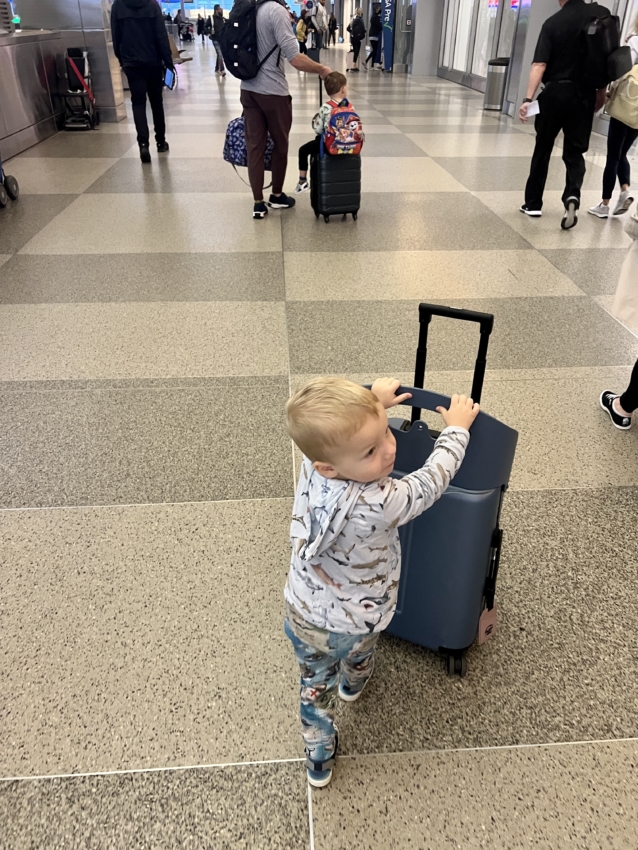 Child pushing ride on suitcase at the airport