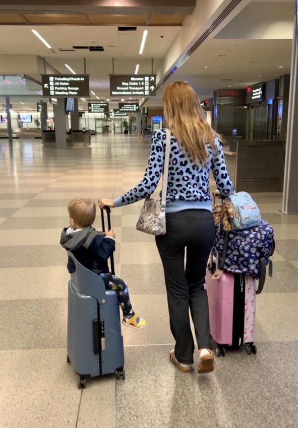 Baby sitting on top of a suitcase with seat