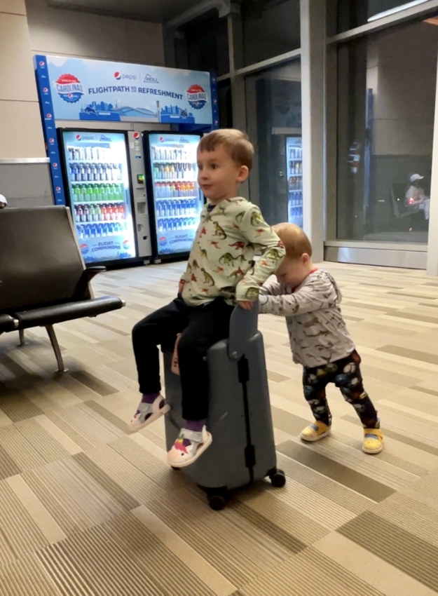 Toddler using ride on suitcase at the airport