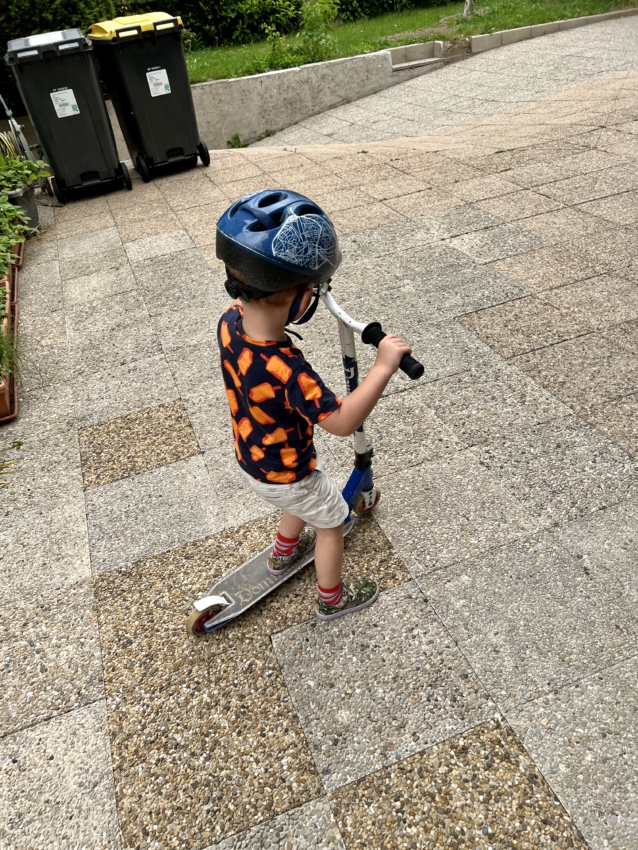 3 year old boy riding a scooter with 2 wheels